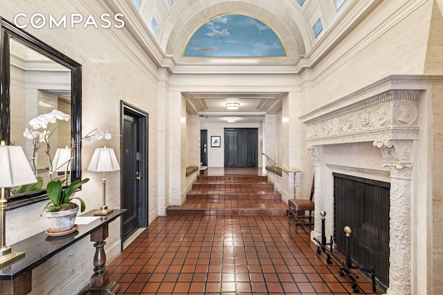 interior space with a high end fireplace, a high ceiling, crown molding, and dark tile patterned flooring