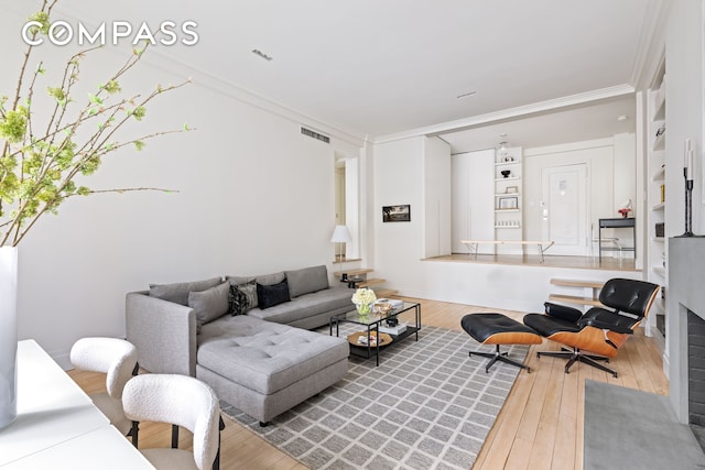 living area with hardwood / wood-style floors, visible vents, and crown molding