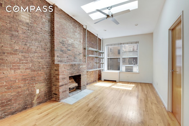 304 W 88th St Unit 4B, New York City, NY 10024 - unfurnished living room with a skylight, hardwood / wood-style flooring, ceiling fan, brick wall, and baseboards