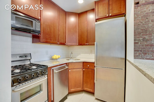 304 W 88th St Unit 4B, New York City, NY 10024 - kitchen featuring appliances with stainless steel finishes, tasteful backsplash, light stone counters, a sink, and brown cabinets