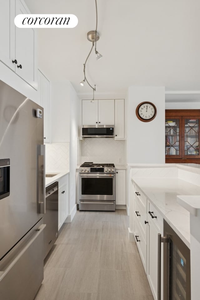 kitchen featuring tasteful backsplash, white cabinets, appliances with stainless steel finishes, and beverage cooler