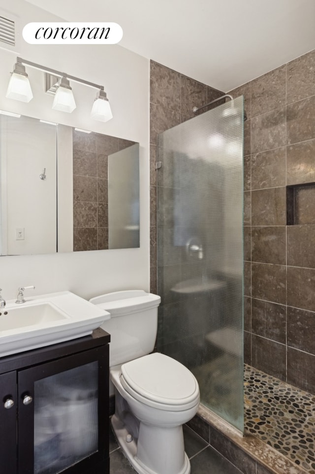 bathroom featuring tile patterned flooring, a shower stall, toilet, vanity, and visible vents
