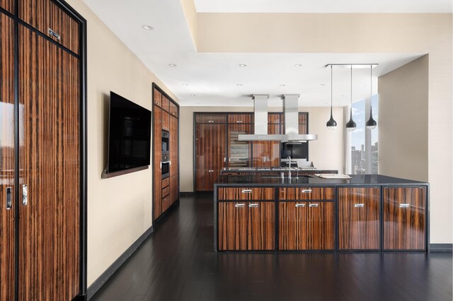 kitchen with pendant lighting, dark countertops, modern cabinets, extractor fan, and dark wood-type flooring