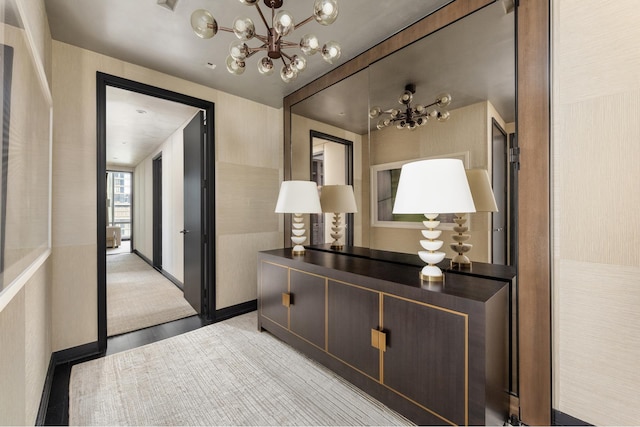 corridor with an inviting chandelier, baseboards, and light wood-type flooring