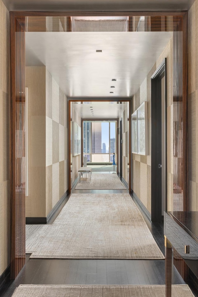 hall with wood finished floors and wallpapered walls