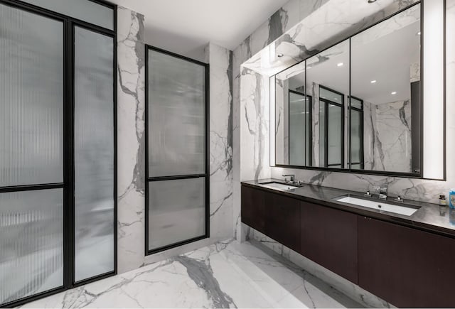 bathroom featuring double vanity, stone wall, a sink, and marble finish floor