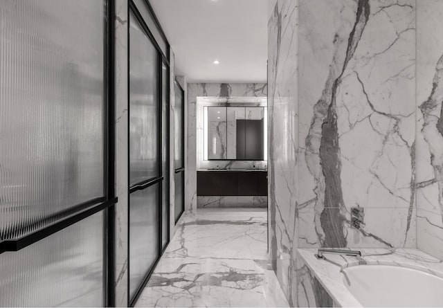 full bath featuring vanity, a bath, and marble finish floor