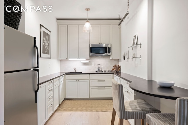 201 E 21st St Unit 12M, New York City, NY 10010 - kitchen with appliances with stainless steel finishes, dark countertops, tasteful backsplash, light wood-style flooring, and a sink
