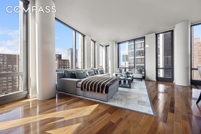 living room with expansive windows, hardwood / wood-style flooring, and a view of city