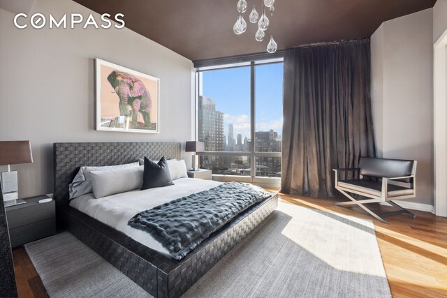 bedroom with a wall of windows, a skyline view, and wood finished floors