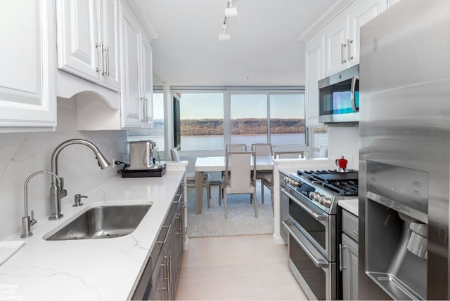 kitchen with appliances with stainless steel finishes, a sink, decorative backsplash, and white cabinets