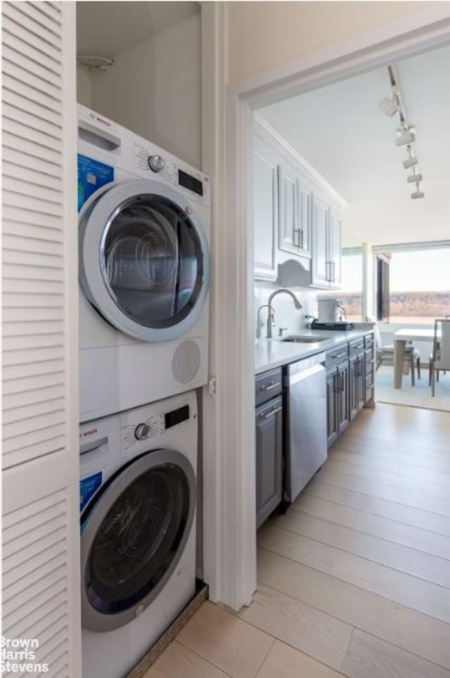 washroom featuring track lighting and stacked washer and clothes dryer
