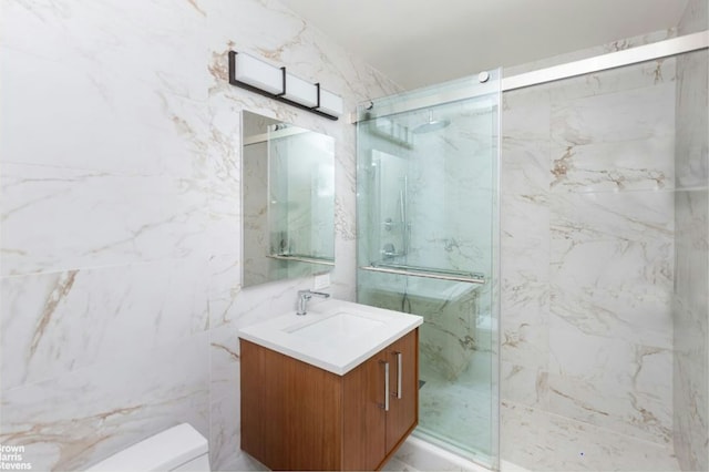 bathroom featuring a marble finish shower, vanity, tile walls, and toilet