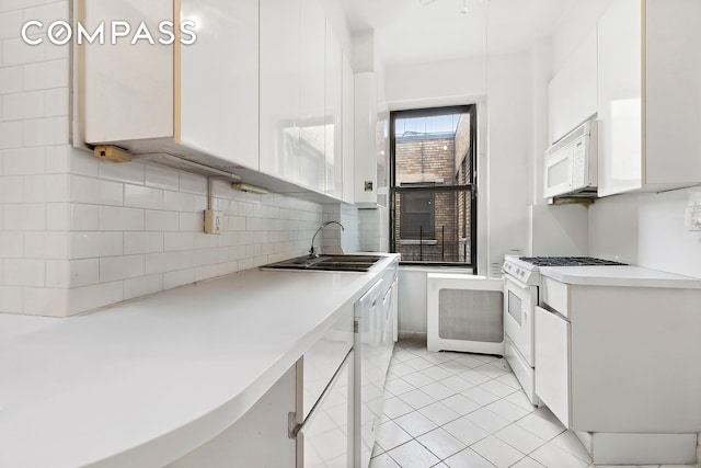 215 W 92nd St Unit 15A, New York City, NY 10025 - kitchen featuring white appliances, decorative backsplash, white cabinets, and a sink