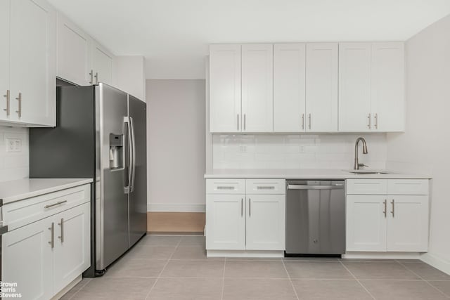 kitchen featuring baseboards, a sink, decorative backsplash, and stainless steel appliances