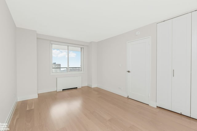unfurnished bedroom featuring baseboards, light wood finished floors, and a closet