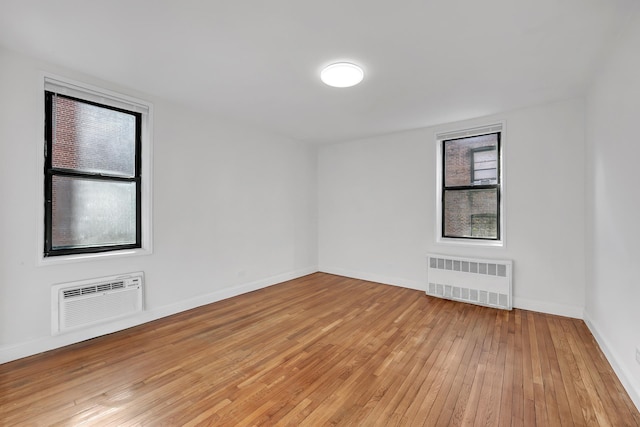 spare room featuring radiator, light wood-style flooring, and baseboards