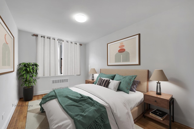 bedroom with radiator heating unit, wood finished floors, and baseboards