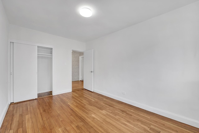 unfurnished bedroom with light wood-style flooring, a closet, and baseboards