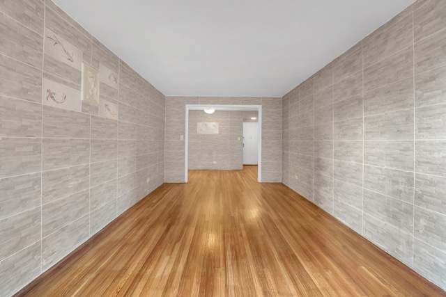 empty room featuring tile walls and wood finished floors