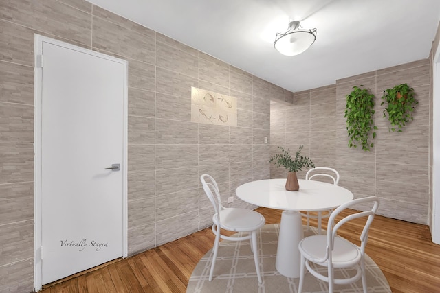 dining room with tile walls and wood finished floors