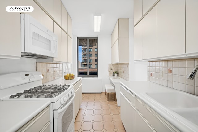 kitchen featuring white appliances, a sink, light countertops, backsplash, and white cabinets