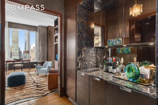 252 E 57th St Unit 60A, New York City, NY 10022 - bar area featuring a sink, light wood-style flooring, and a chandelier