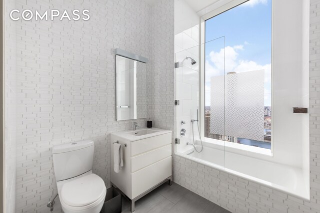 252 E 57th St Unit 60A, New York City, NY 10022 - full bath with tiled shower / bath, tile walls, toilet, vanity, and tile patterned flooring