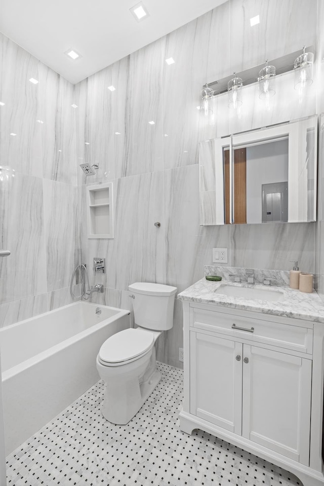 full bath with toilet, shower / tub combination, vanity, and tile walls