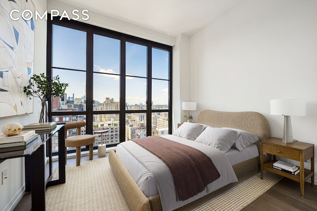 bedroom with a view of city and wood finished floors