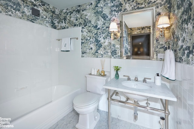 full bathroom with a sink, toilet, tile walls, wallpapered walls, and shower / washtub combination
