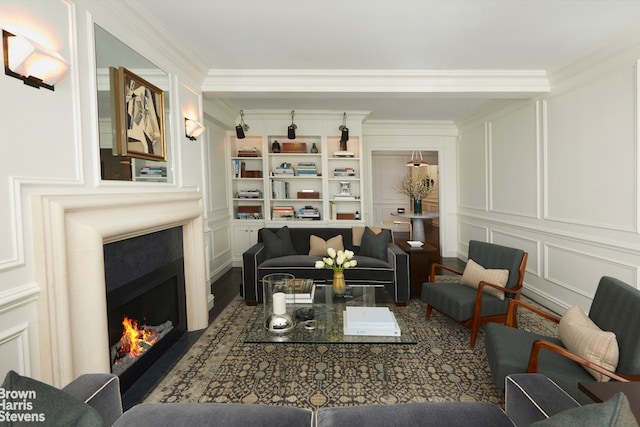 sitting room with a decorative wall, ornamental molding, a lit fireplace, and wood finished floors