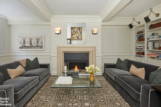 living area with crown molding, built in features, a warm lit fireplace, and a decorative wall