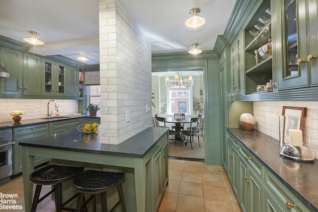 kitchen with a sink, a notable chandelier, backsplash, green cabinets, and open shelves