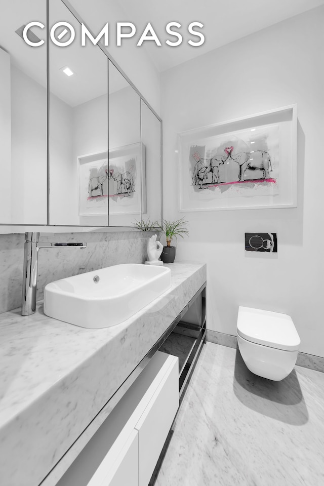 bathroom featuring vanity, toilet, and baseboards