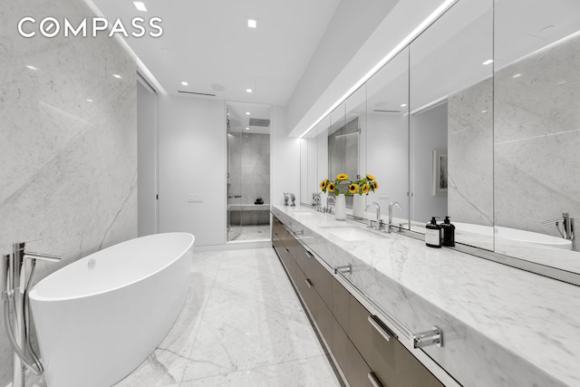 bathroom with tile walls, double vanity, marble tiled flooring, a stall shower, and a soaking tub