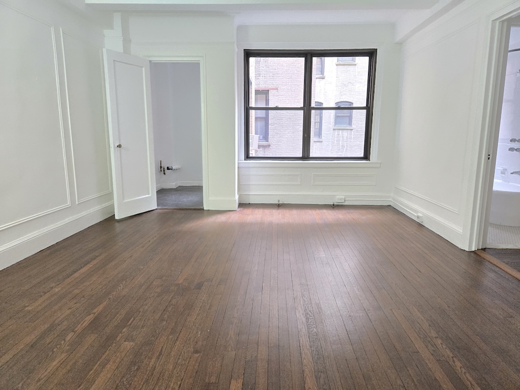 162 W 56th St Unit 1101, New York City, NY 10019 - spare room featuring dark wood-type flooring and a decorative wall