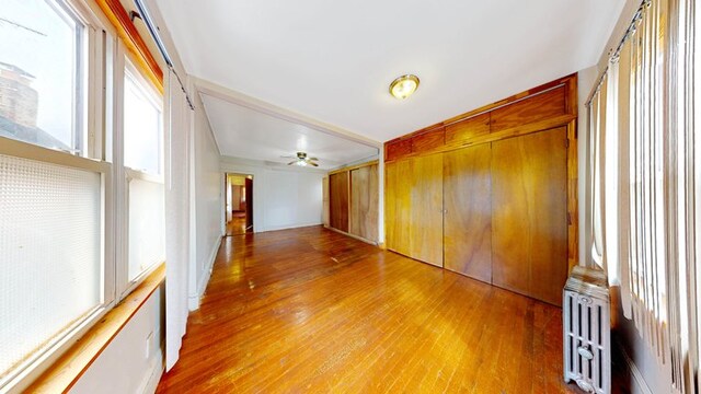 empty room with radiator, light wood-style flooring, and ceiling fan