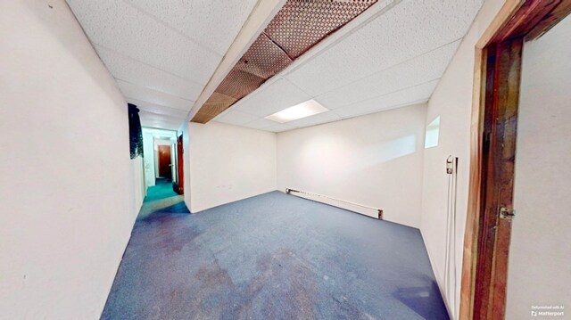 finished basement featuring a baseboard heating unit and a paneled ceiling
