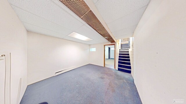 below grade area featuring baseboard heating, stairs, and a paneled ceiling