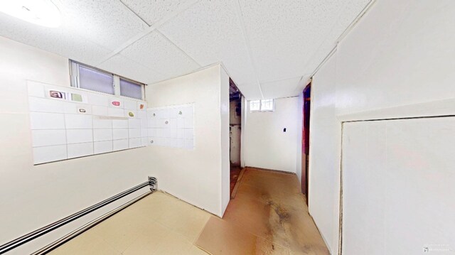 hallway featuring a baseboard heating unit and a paneled ceiling