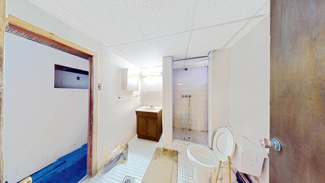 bathroom with a shower stall, tile patterned flooring, a drop ceiling, toilet, and vanity