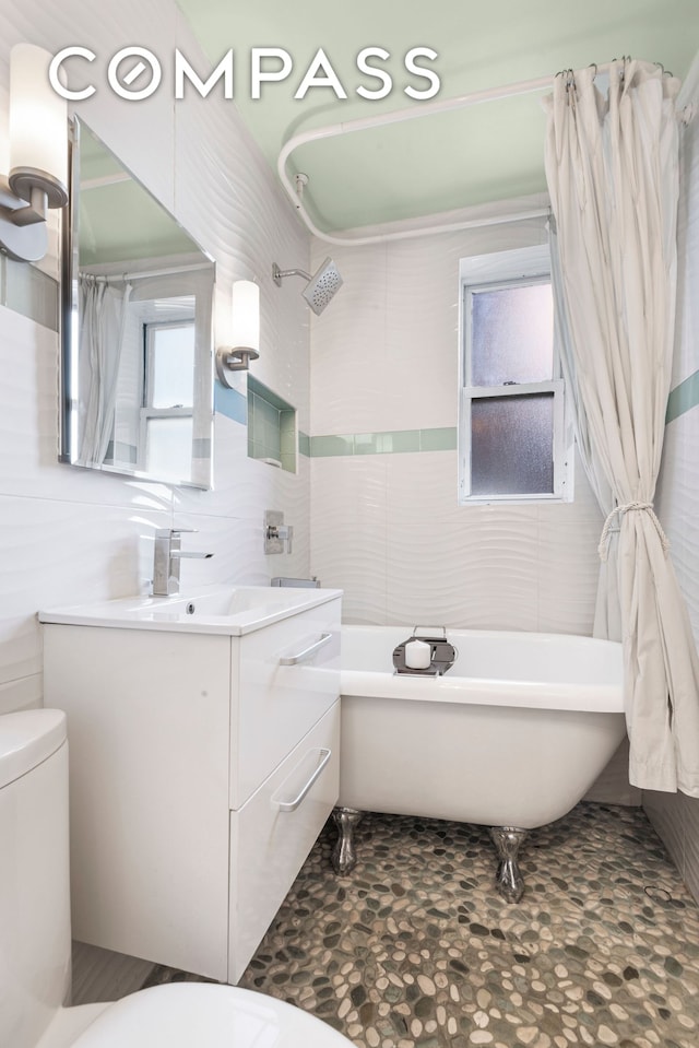 61 Oliver St Unit 4P, New York City, NY 11209 - full bathroom featuring tile walls, toilet, a soaking tub, and vanity