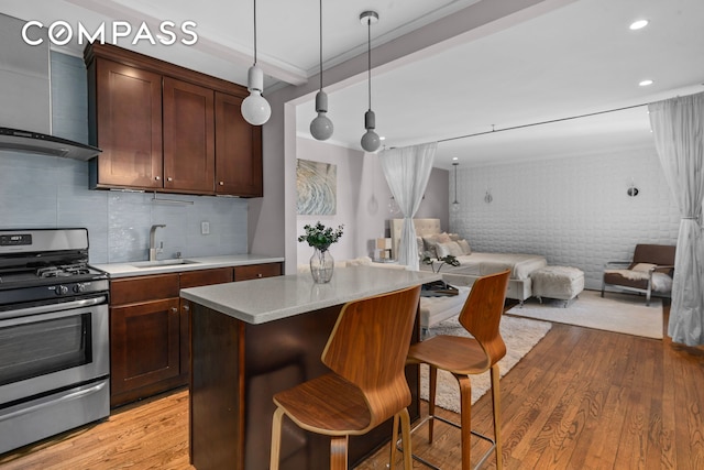 61 Oliver St Unit 4P, New York City, NY 11209 - kitchen with stainless steel gas stove, a sink, wall chimney exhaust hood, open floor plan, and light wood-type flooring
