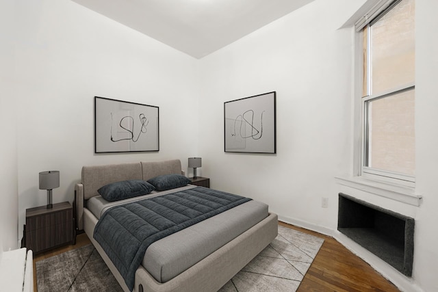 bedroom featuring baseboard heating, wood finished floors, and baseboards