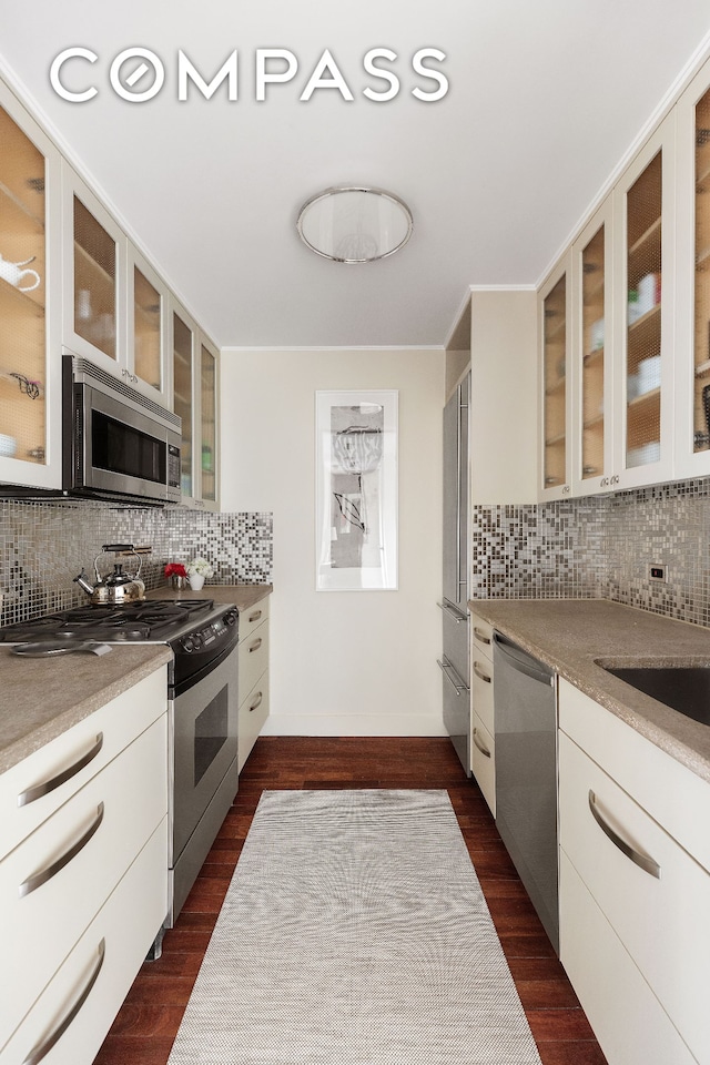 1965 Broadway Unit 14C, New York City, NY 10023 - kitchen featuring appliances with stainless steel finishes, backsplash, and glass insert cabinets