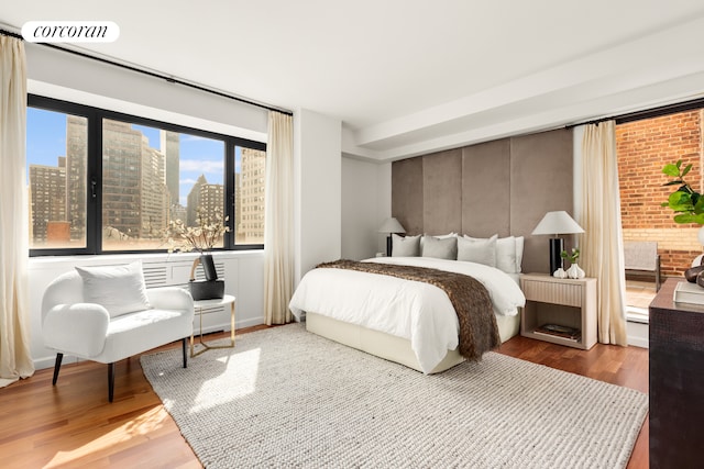 bedroom with a view of city and wood finished floors