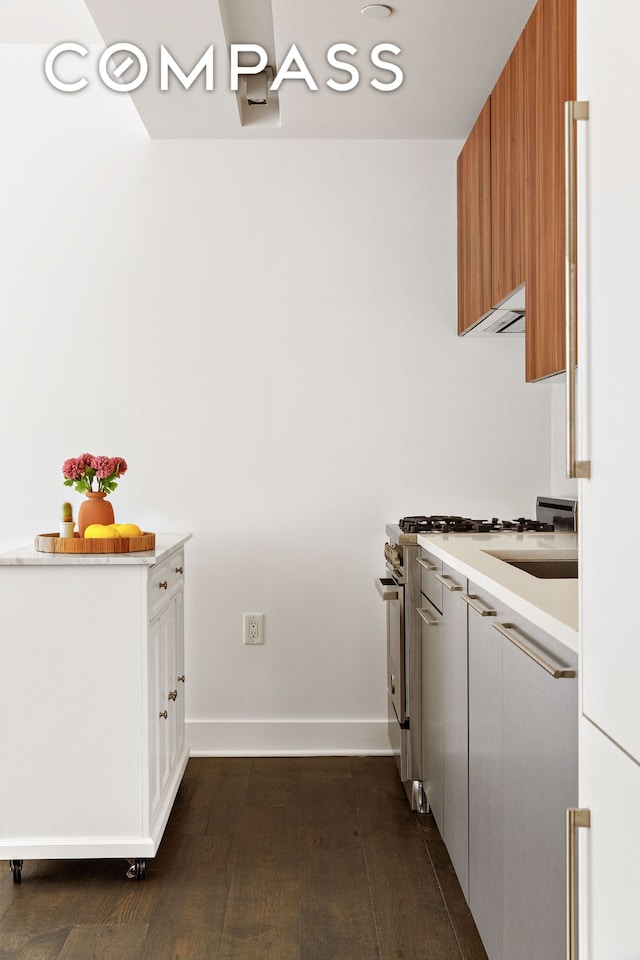 kitchen with high end range, light countertops, dark wood-style floors, and white cabinets