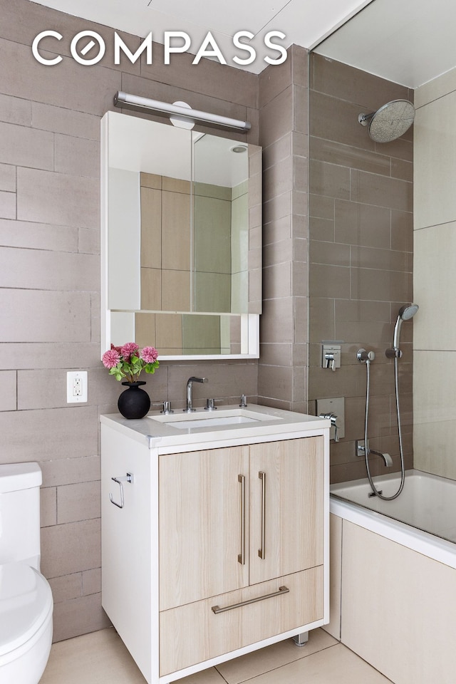 full bath with toilet, vanity, tile walls, and tile patterned floors