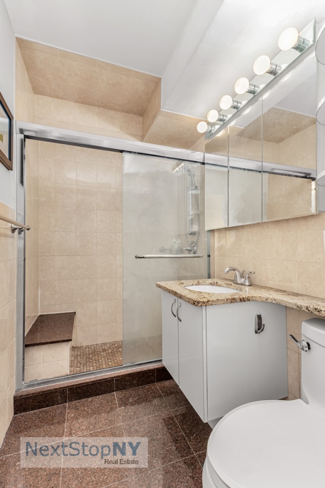 330 E 49th St Unit 6J, New York City, NY 10017 - bathroom featuring toilet, granite floors, vanity, a shower stall, and tile walls